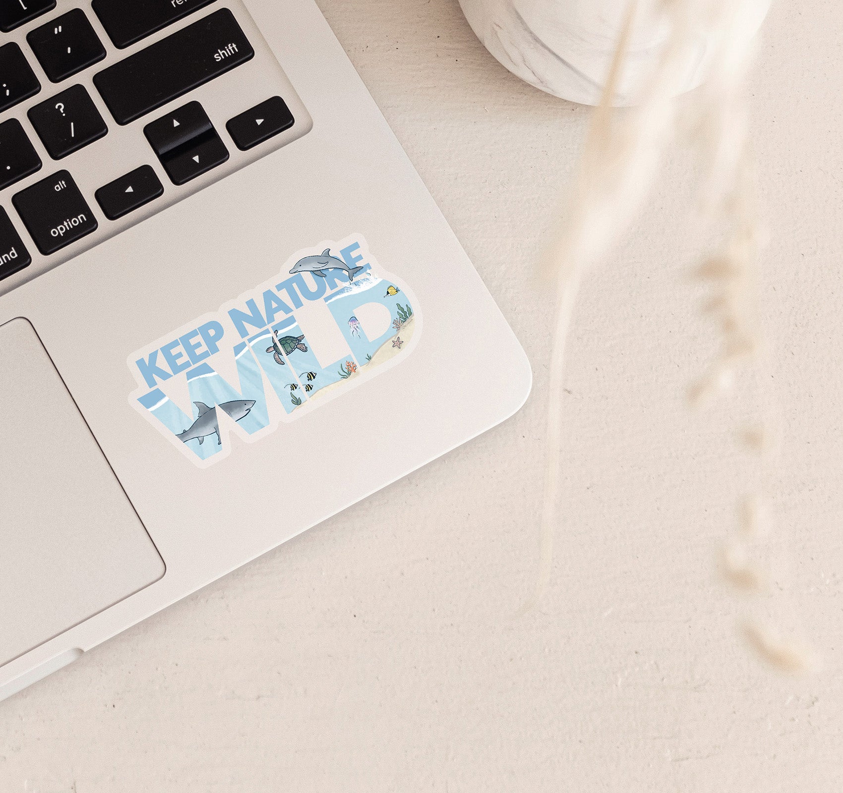 Keep Nature Wild laptop sticker with a great white shark, bottlenose dolphin, green sea turtle, jellyfish, and various fish swimming in the ocean