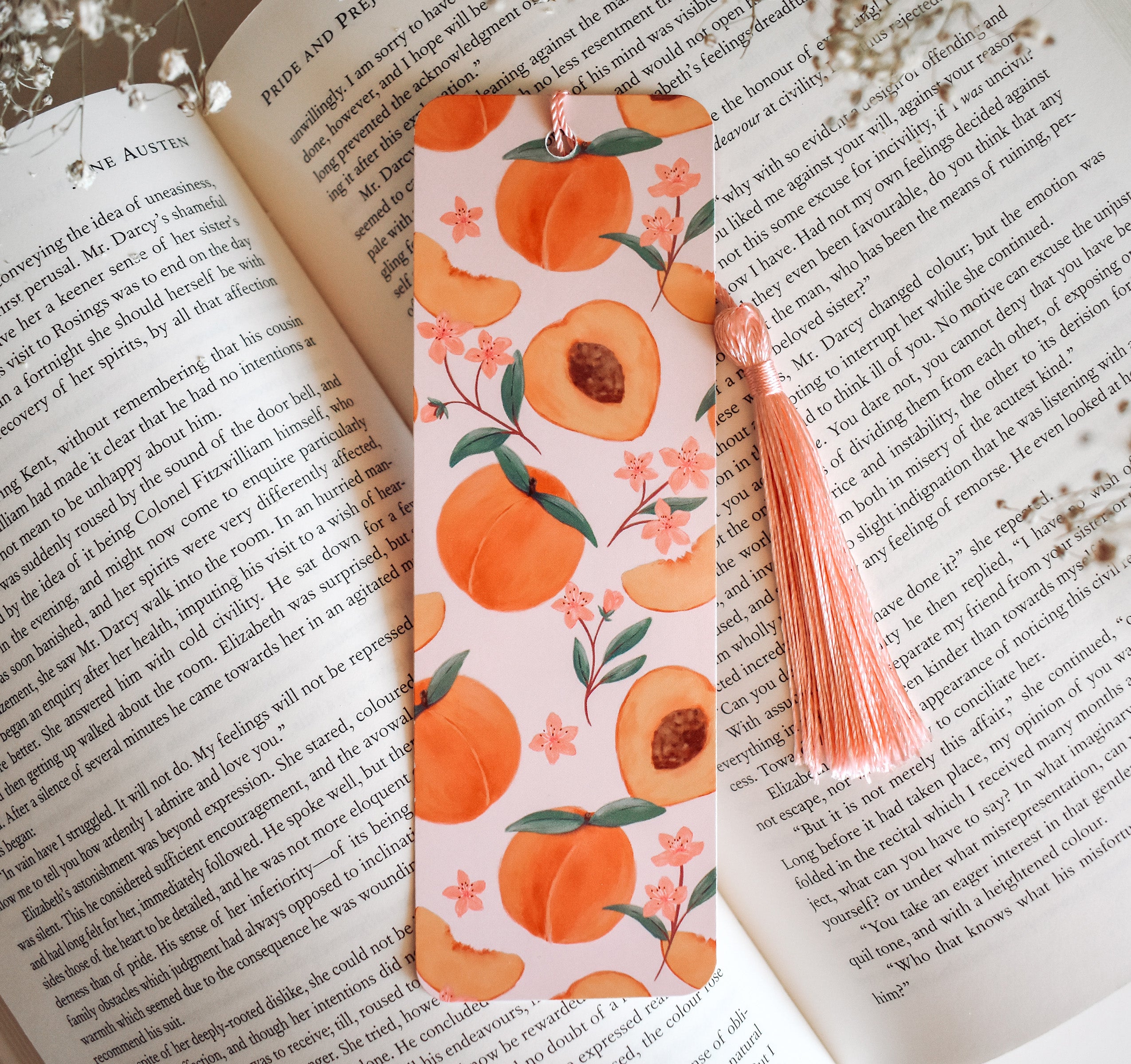 Bookmark with peach artwork design printed on both sides and a pink tassel