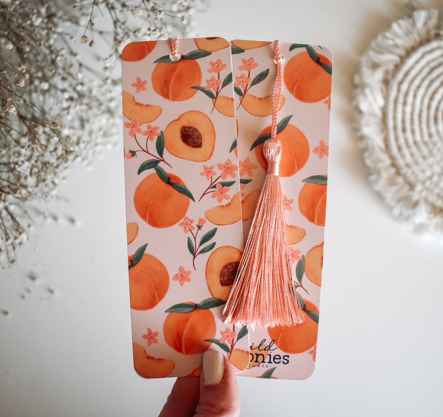 Bookmark with peach artwork design printed on both sides and a pink tassel