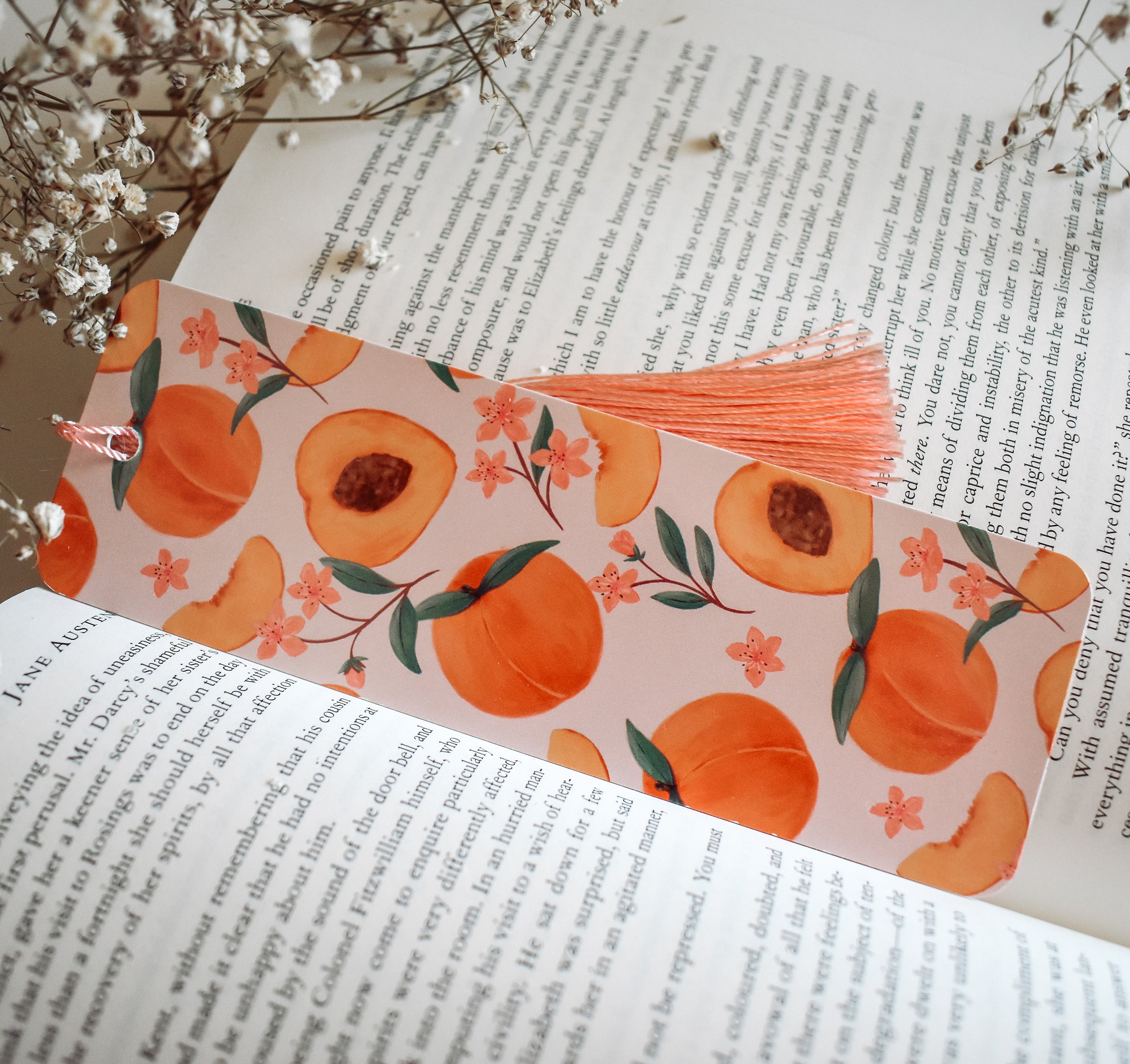 Bookmark with peach artwork design printed on both sides and a pink tassel