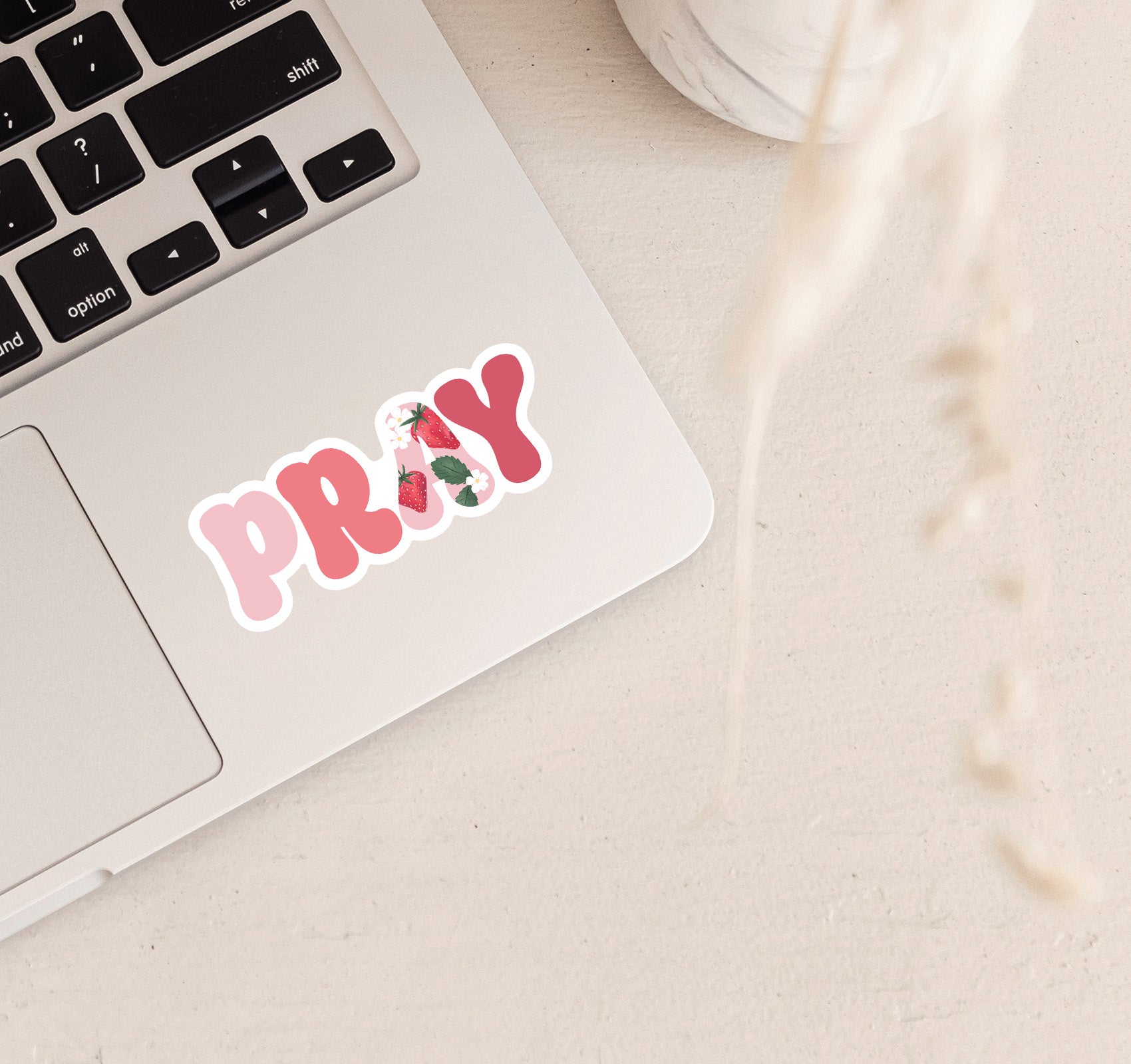 Pink PRAY vinyl sticker on a laptop with a strawberry design