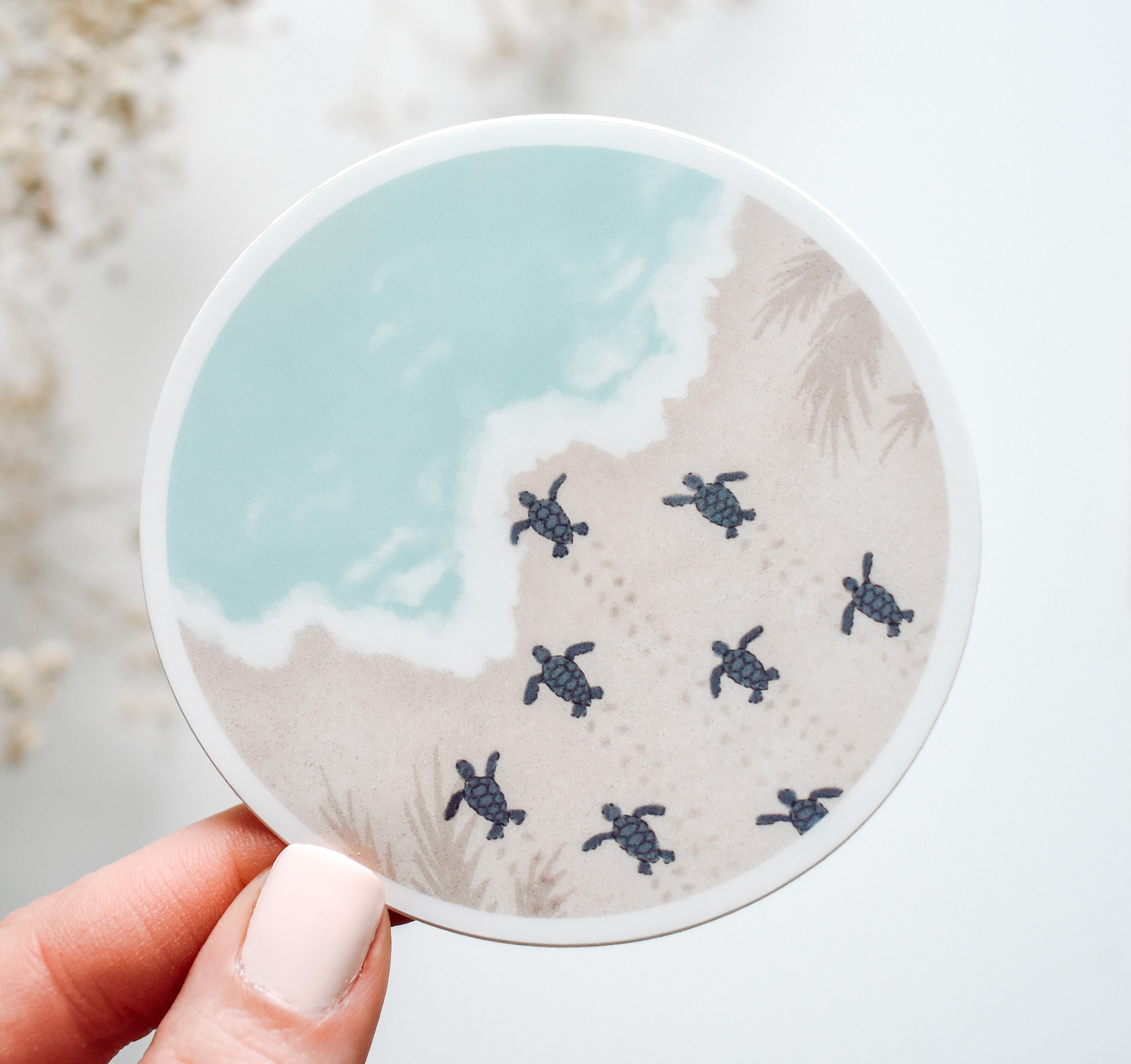 Round vinyl sticker with baby sea turtles moving across the sand towards the ocean