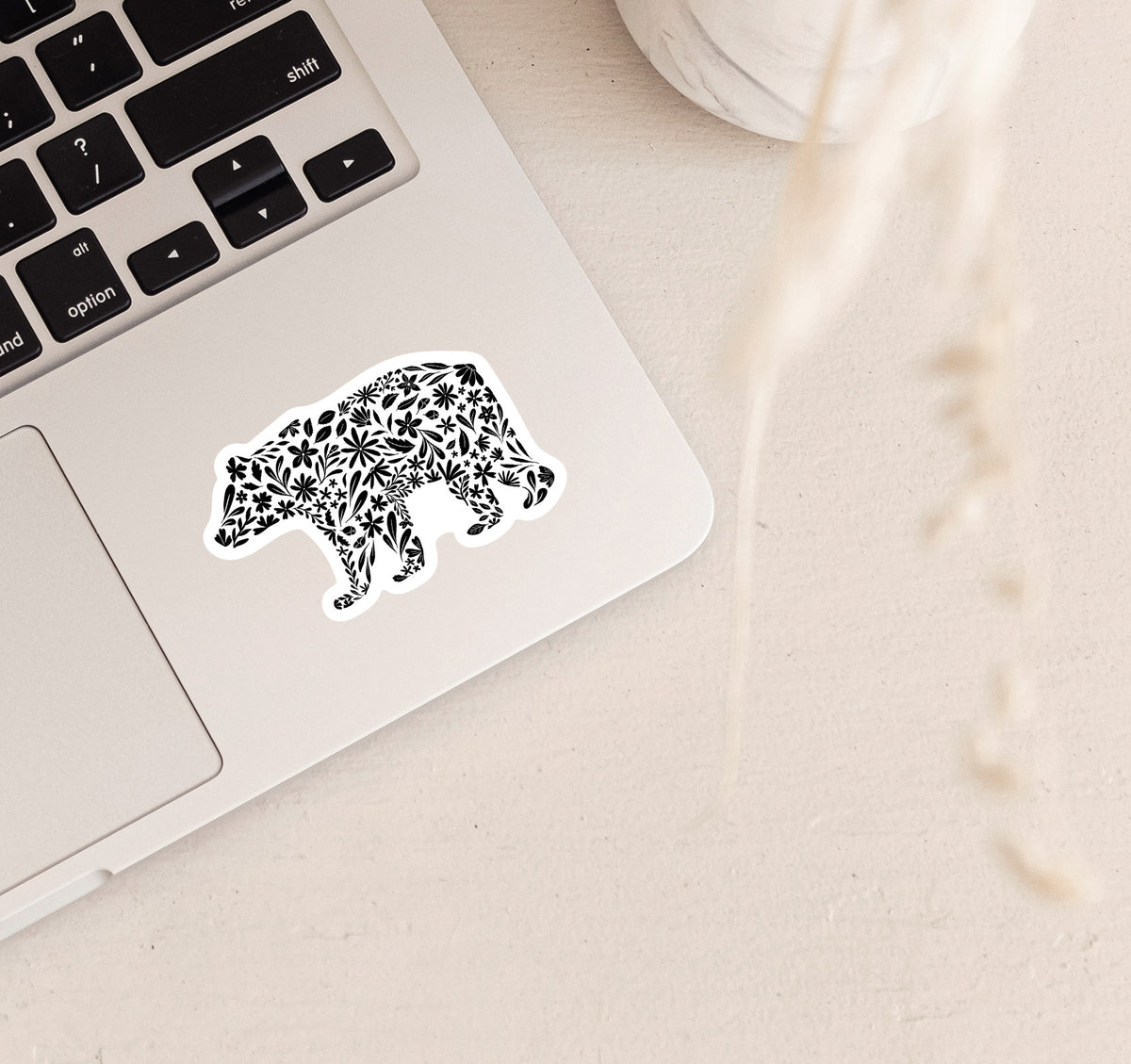 Decorative bear sticker on a laptop with black floral patterns