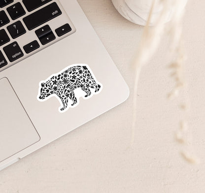 Decorative bear sticker on a laptop with black floral patterns