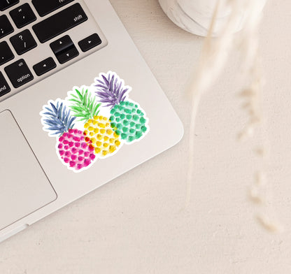 A collection of three colorful pineapples on a vinyl laptop sticker