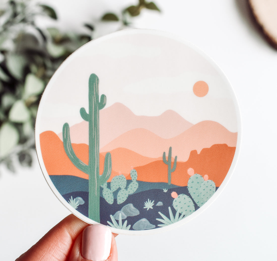 Round boho sticker of desert scenery with a saguaro cactus and the mountains at sunset