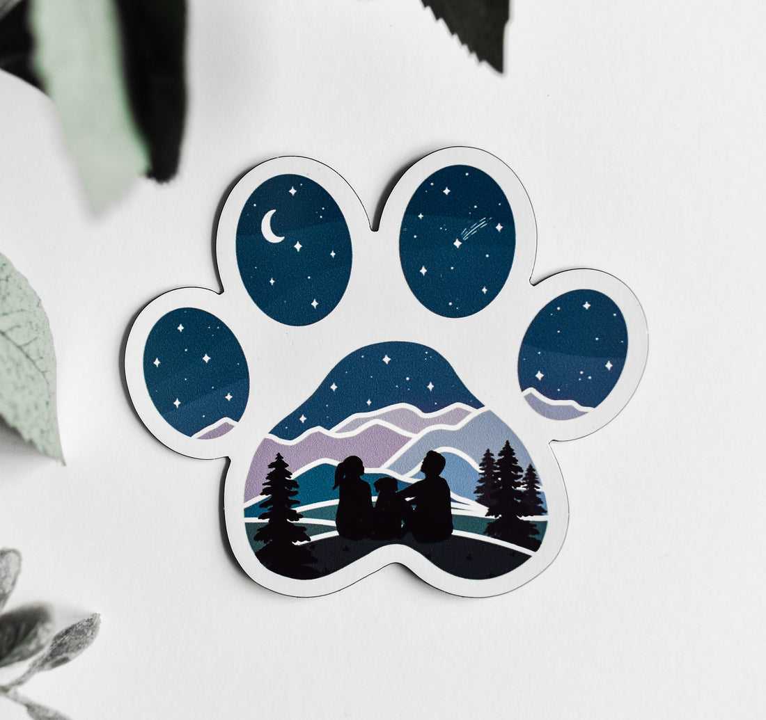 A couple and their dog watching the stars and moon as a magnet in the shape of a dog paw print