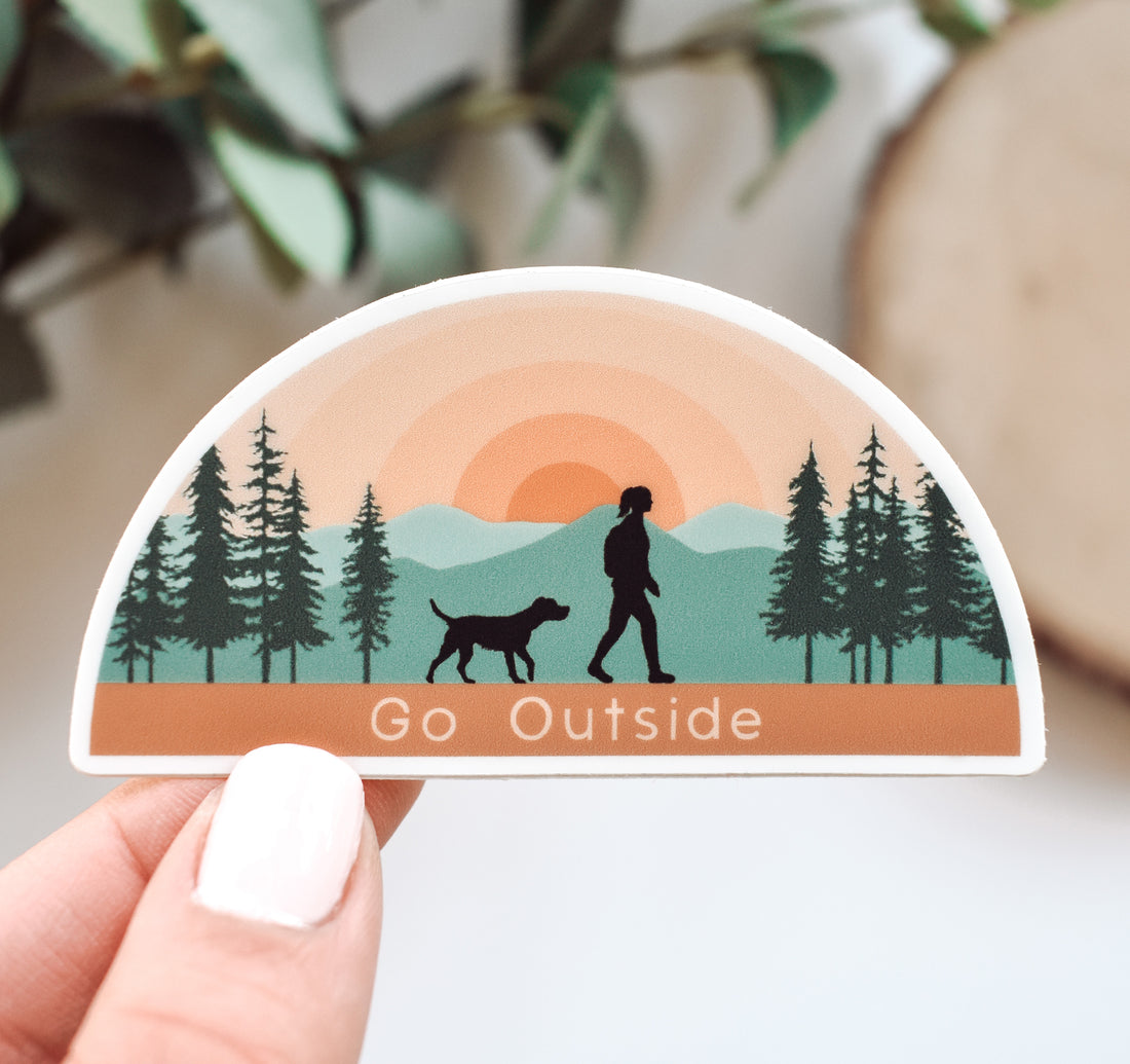 Hiking sticker of a girl and dog at sunset in the mountains