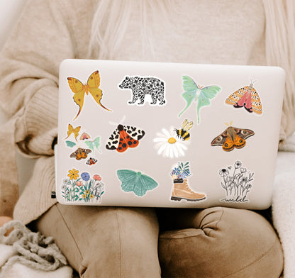 A laptop decorated with various colorful butterfly, moth, flower, and animal stickers.