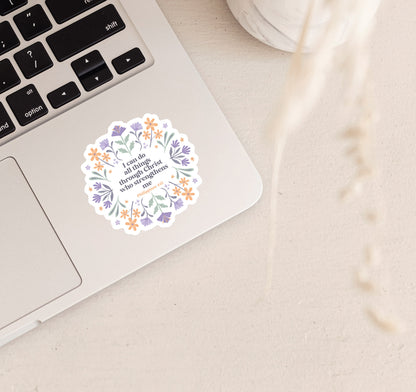 Decorative Christian faith sticker with the Bible verse "I can do all things through Christ who strengthens me, Philippians 4:13" surrounded by hand-drawn purple and orange flowers, located on a silver laptop