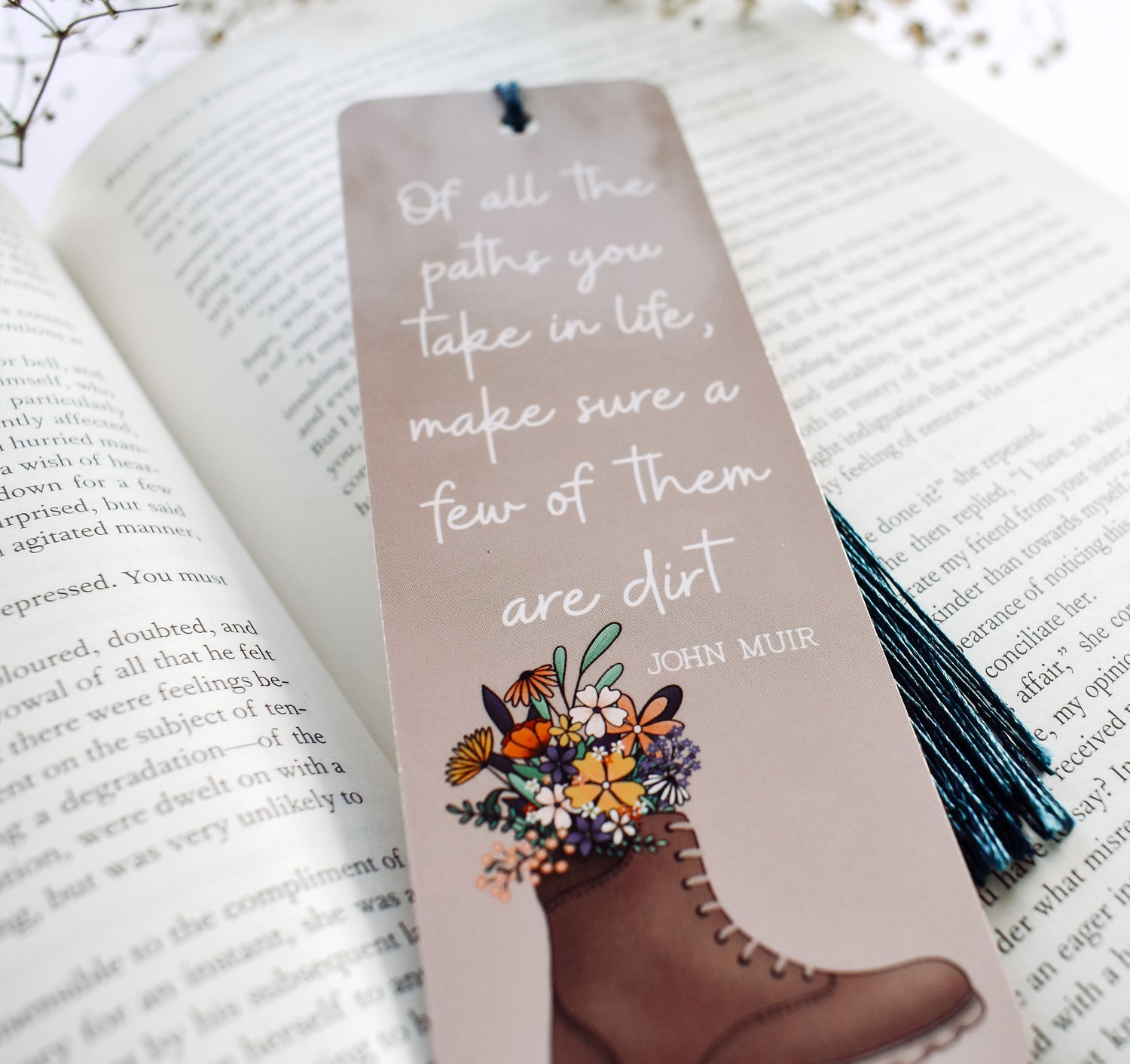 Bookmark with the John Muir quote &quot;Of all the paths you take in life, make sure a few of them are dirt&quot; and a hiking boot with flowers design