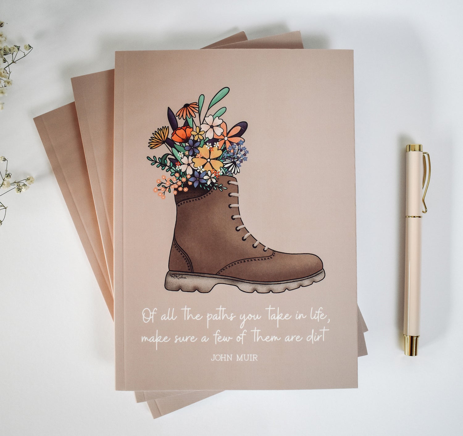 John Muir quote notebook with a hiking boot full of flowers