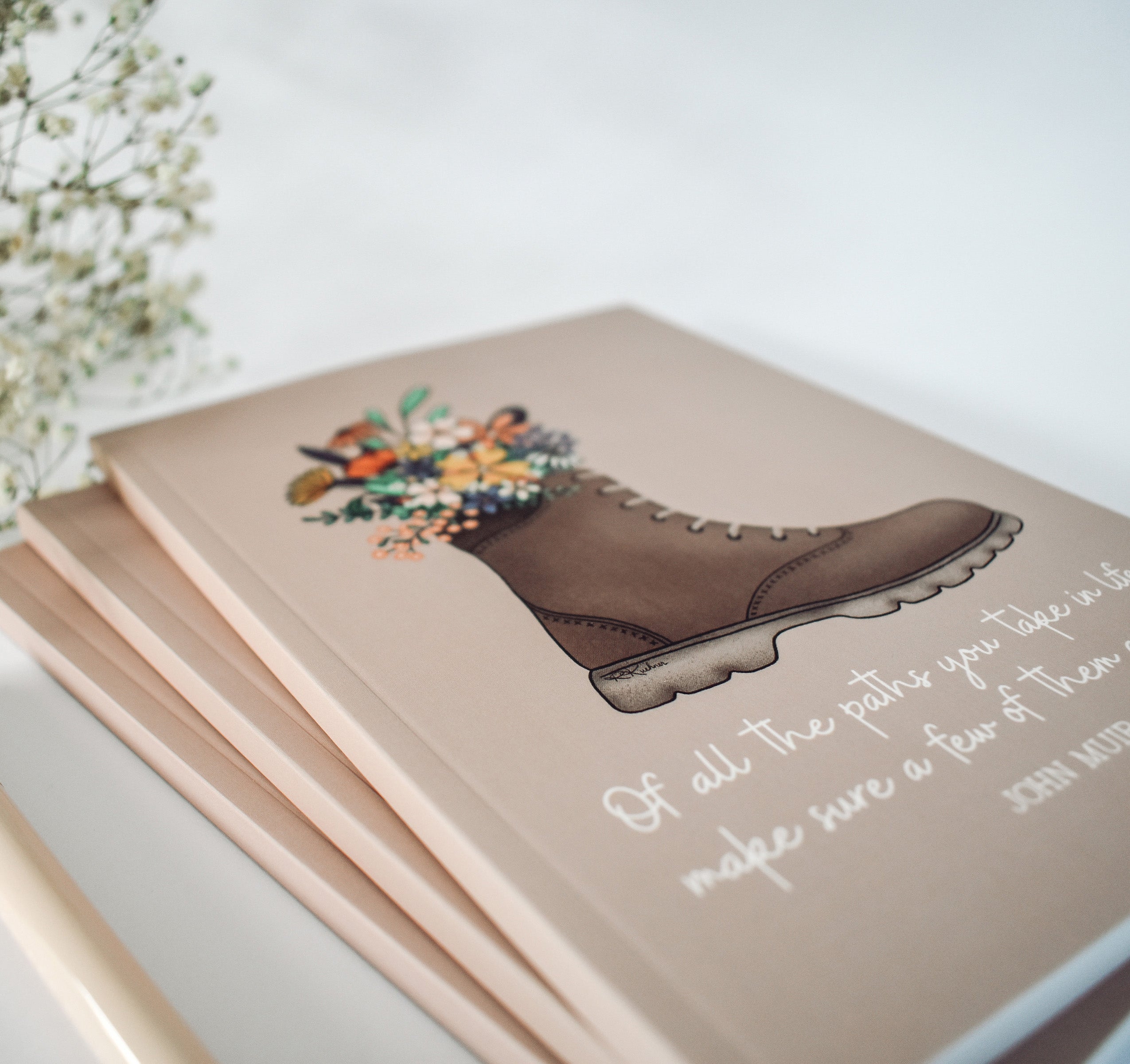 John Muir quote notebook with a hiking boot full of flowers
