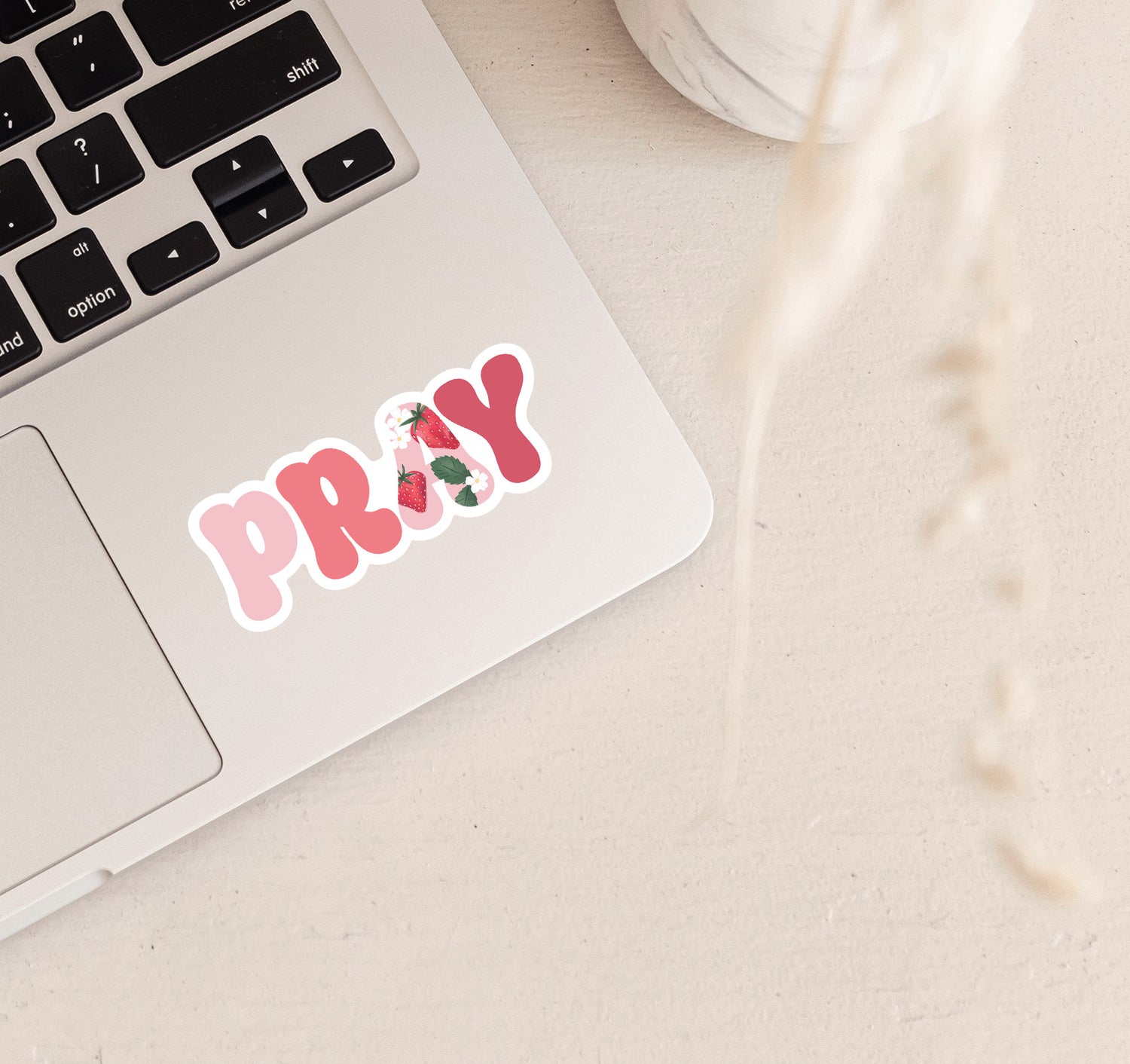 Pink PRAY vinyl sticker on a laptop with a strawberry design