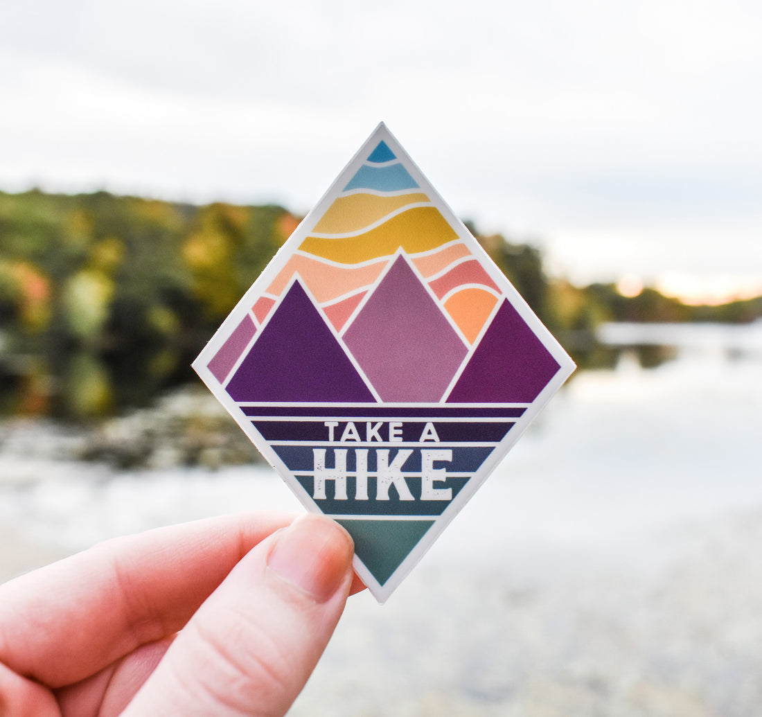 Take a hike sticker with mountains at sunset