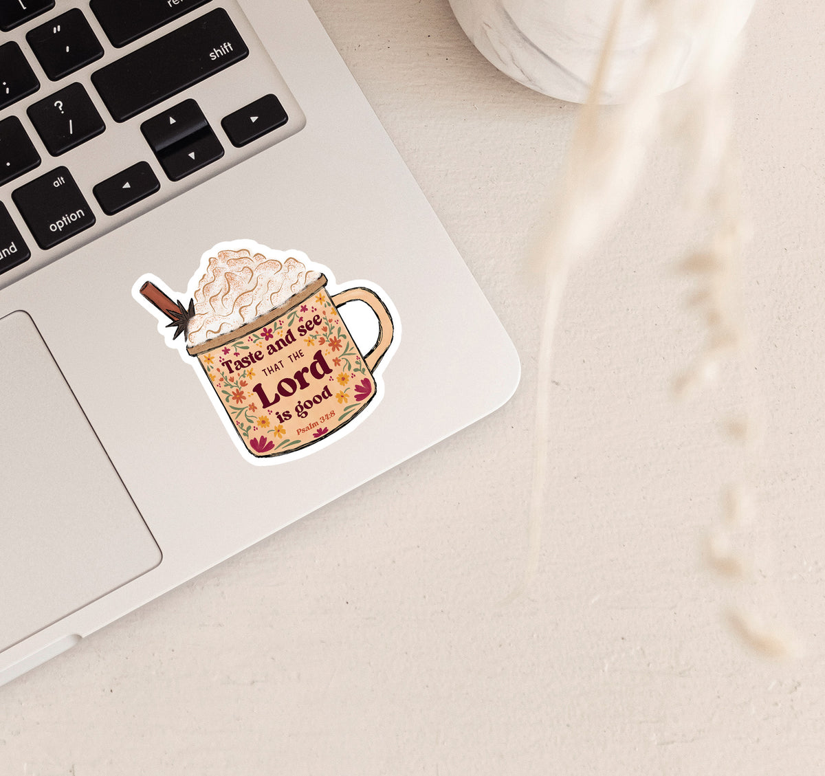 A die-cut sticker featuring a mug filled with whipped cream and a cinnamon stick, with the text &