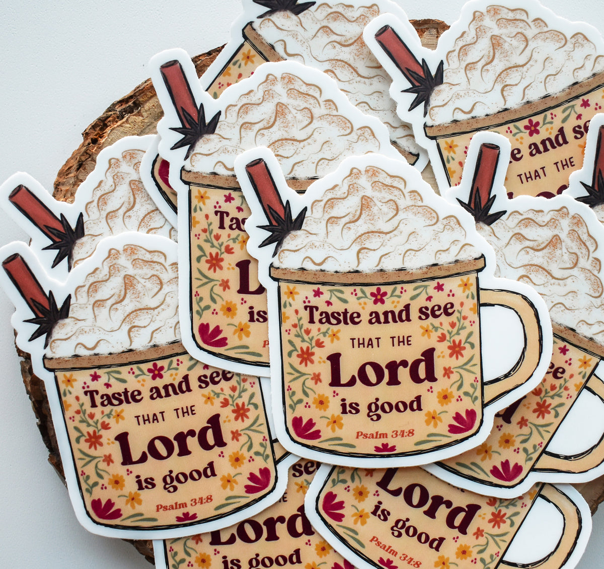 A pile of die-cut stickers shaped like coffee cups with whipped cream and cinnamon sticks, printed with the phrase &