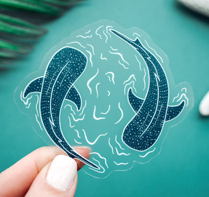 A clear vinyl sticker of two whale sharks swimming in a circle with water lines surrounding them