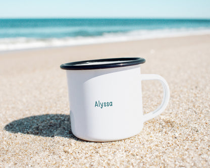 A custom name written on the right side of a personalized metal camp mug